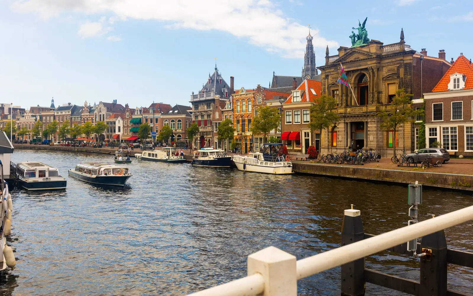 The river Spaarne in Haarlem, with tour boats, the Teylers Museum on the right and the Grote Kerk tower behind