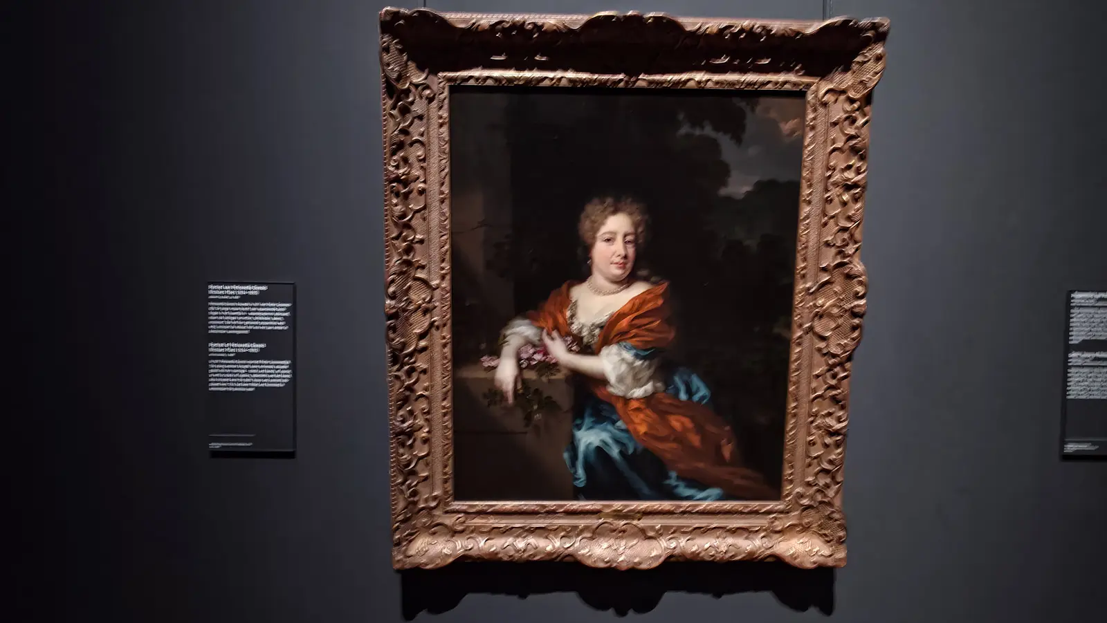 Nicolaes Maes's portrait of Petronella Dunois at the Rijksmuseum, in a blue dress and orange wrap, holding roses