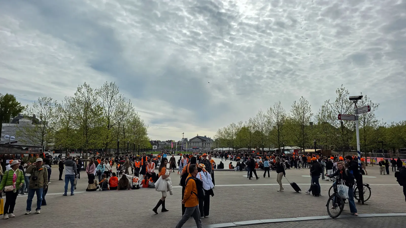 King's Day crowds in orange around the drained pond on Museumplein, with the Concertgebouw at the far end of the square