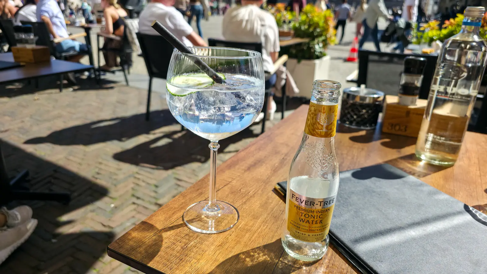 A classic gin and tonic with cucumber beside a bottle of Fever-Tree Indian tonic on a 't Nieuwe Kafe table