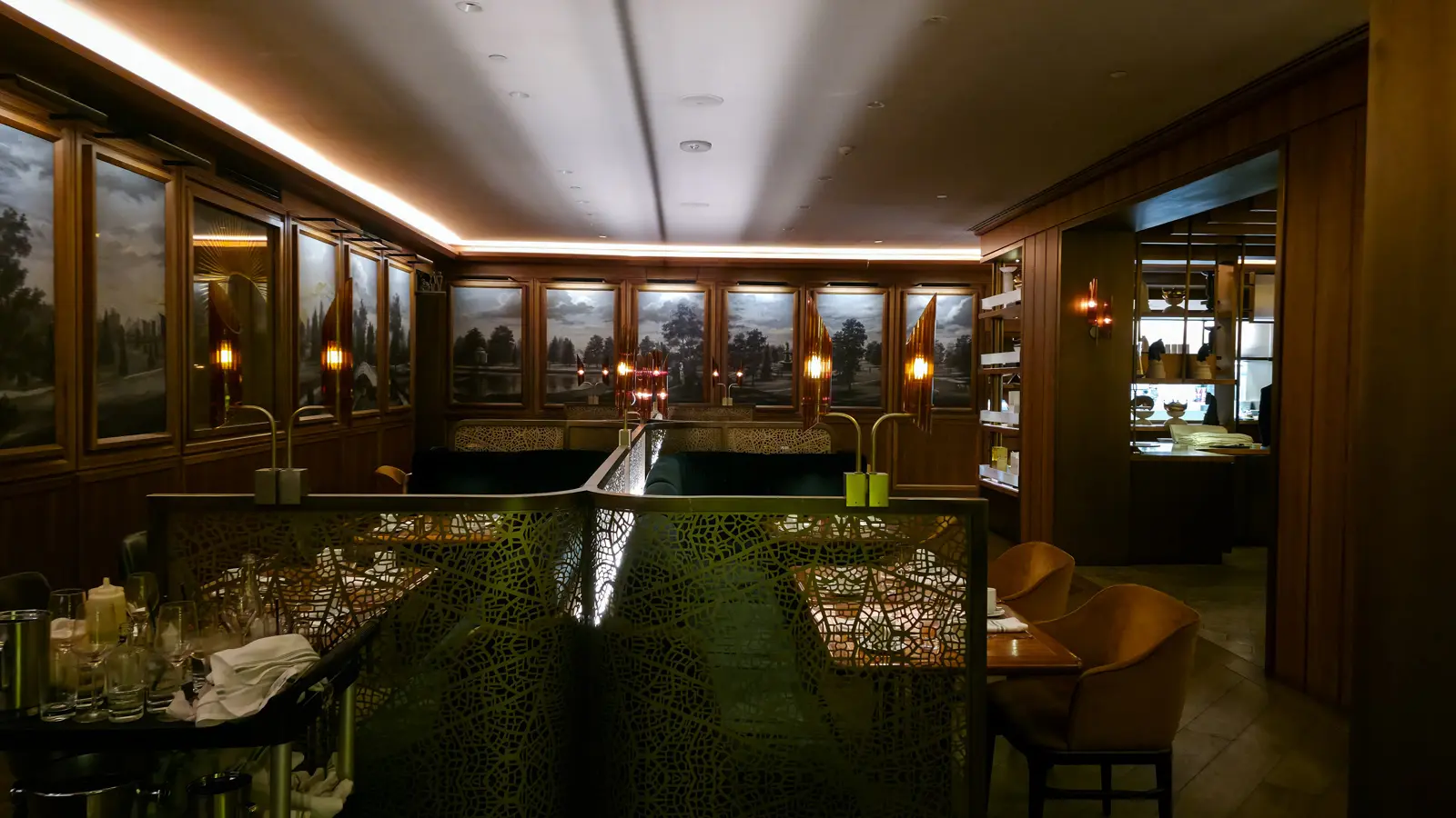 Booths behind metal leaf-pattern screens, with amber sconces and landscape murals on the walls, Reign restaurant, Toronto