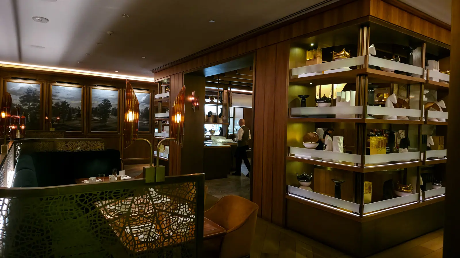 Lit display shelves with gold and black crowns and white horse sculptures beside the open kitchen, Reign restaurant
