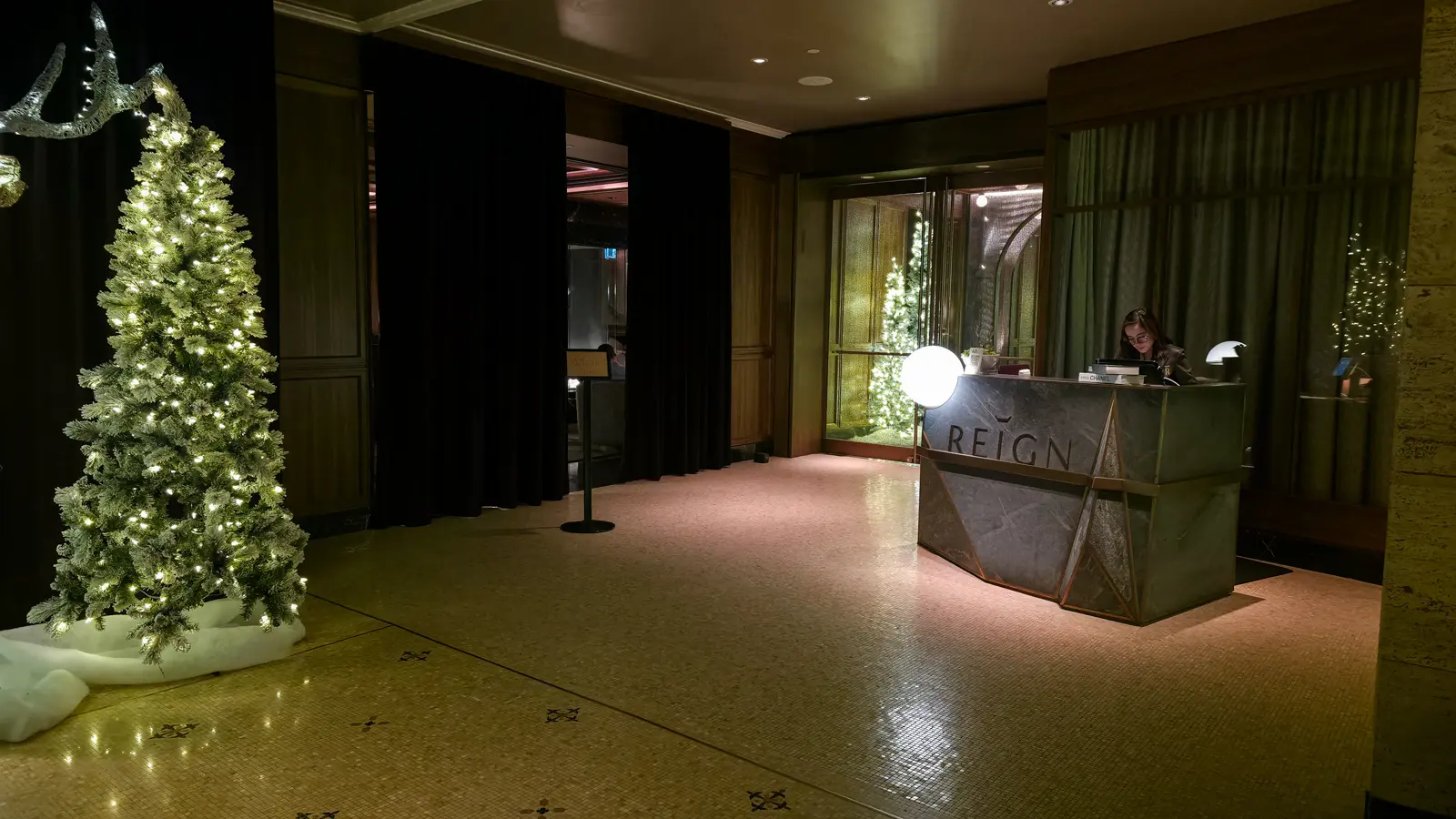 Reign host stand with a lit Christmas tree and a dark curtained entrance to the bar, Fairmont Royal York, Toronto