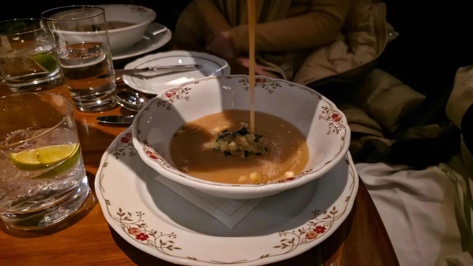 Parsnip velouté being poured over its garnish in a floral-rimmed bowl, Festive Dinner, Reign restaurant, Toronto