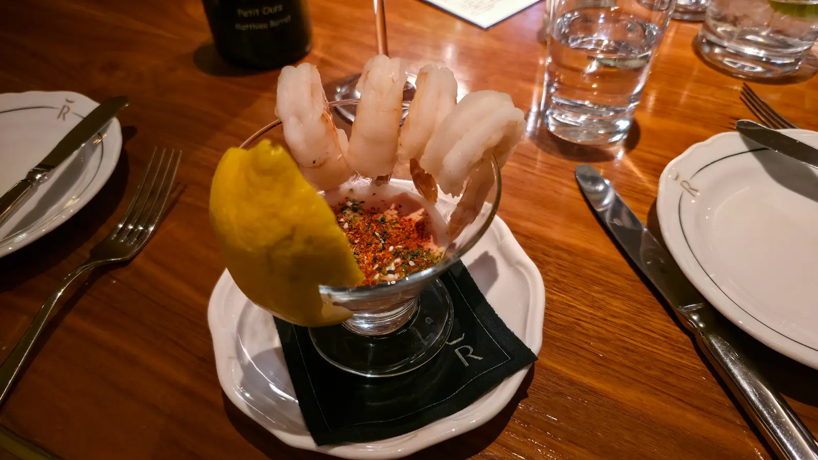 Poached shrimp cocktail with a lemon wedge and spiced Marie Rose sauce, served in a glass coupe, Reign restaurant