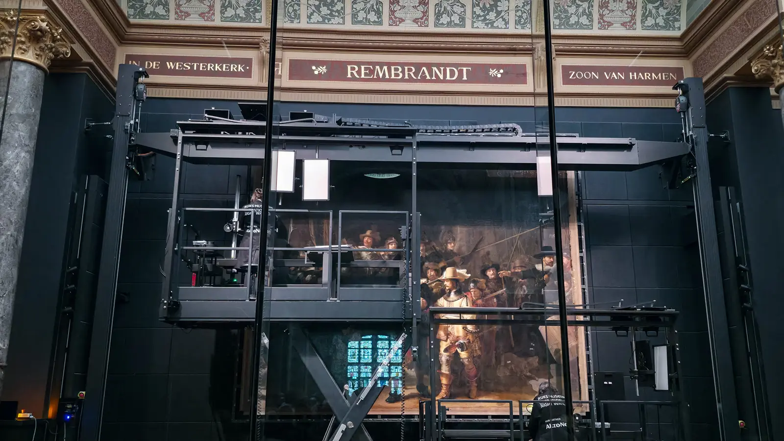 The Night Watch behind glass during Operation Night Watch, under a frieze reading REMBRANDT, Rijksmuseum, Amsterdam