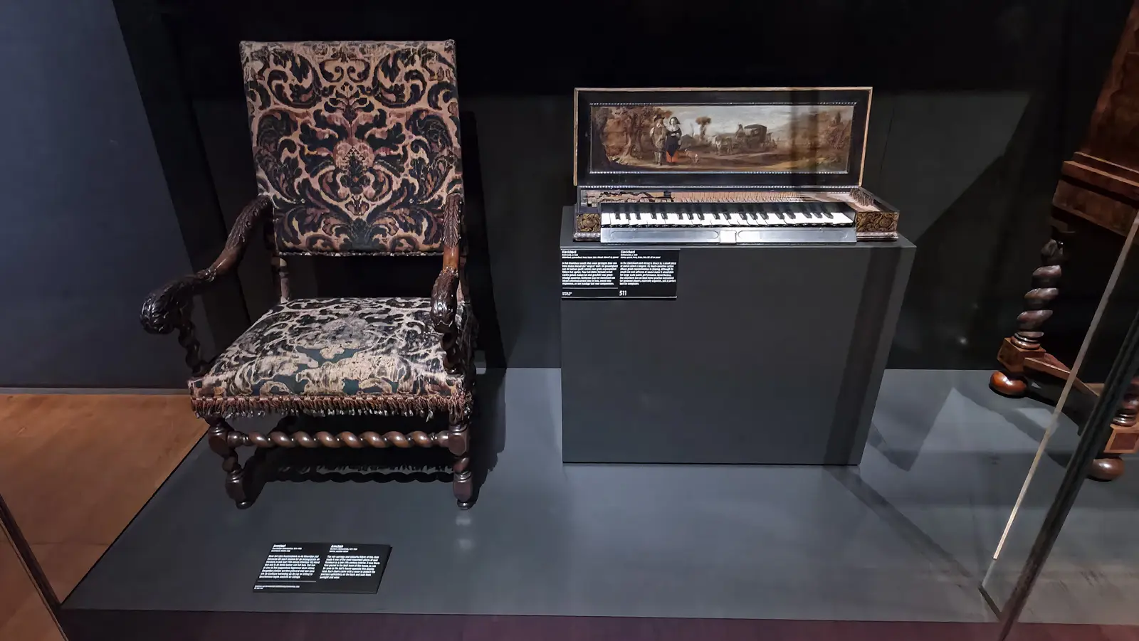 A carved armchair with patterned upholstery beside a clavichord with a painted lid at the Rijksmuseum