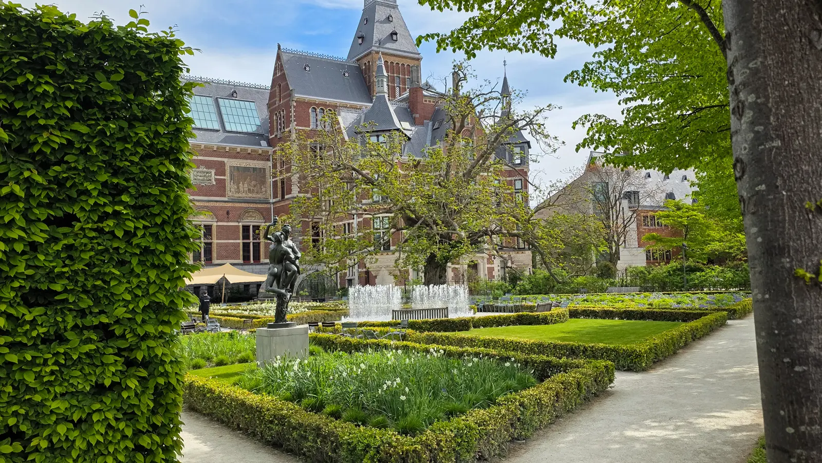 The Rijksmuseum gardens in Amsterdam, with a bronze sculpture, low box hedges and a fountain in front of the museum