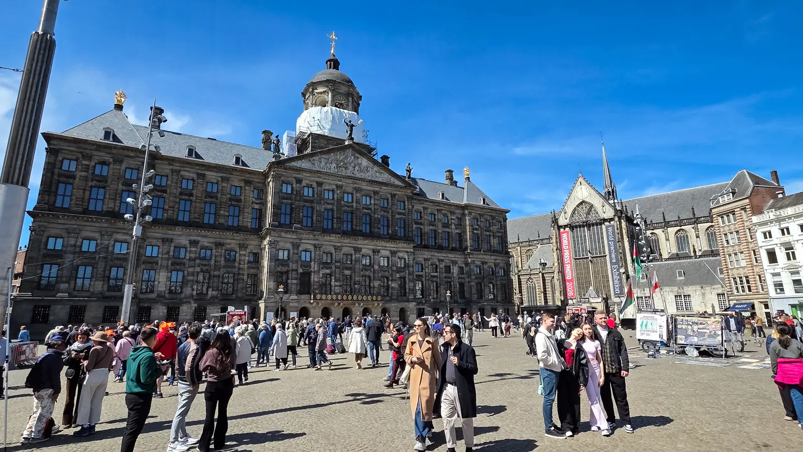 The Royal Palace on Dam Square in Amsterdam, its dome partly wrapped in scaffolding, with the Nieuwe Kerk on the right