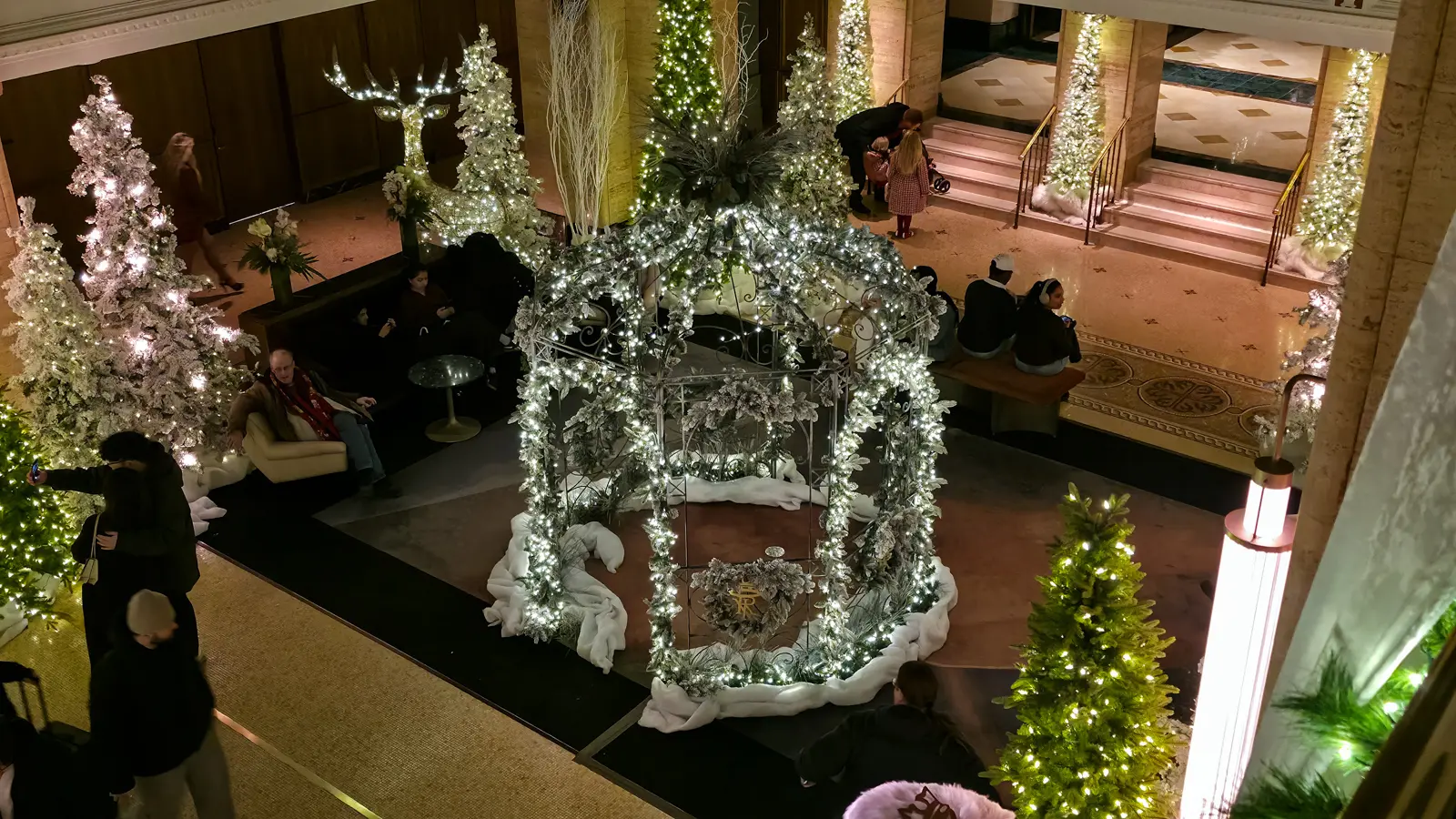 A lit gazebo wrapped in frosted greenery, with the Fairmont Royal York monogram inside, seen from the lobby balcony