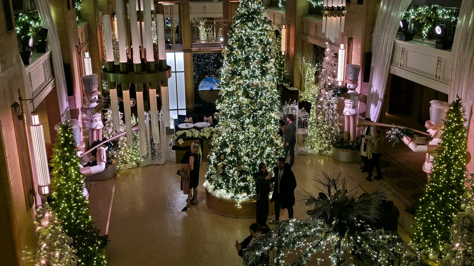 The Fairmont Royal York's Christmas tree in white and gold, flanked by giant nutcrackers and lit trees, seen from the balcony