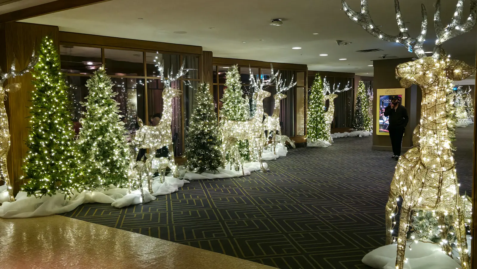 A corridor at the Fairmont Royal York lined with lit Christmas trees and glittering reindeer on fake snow