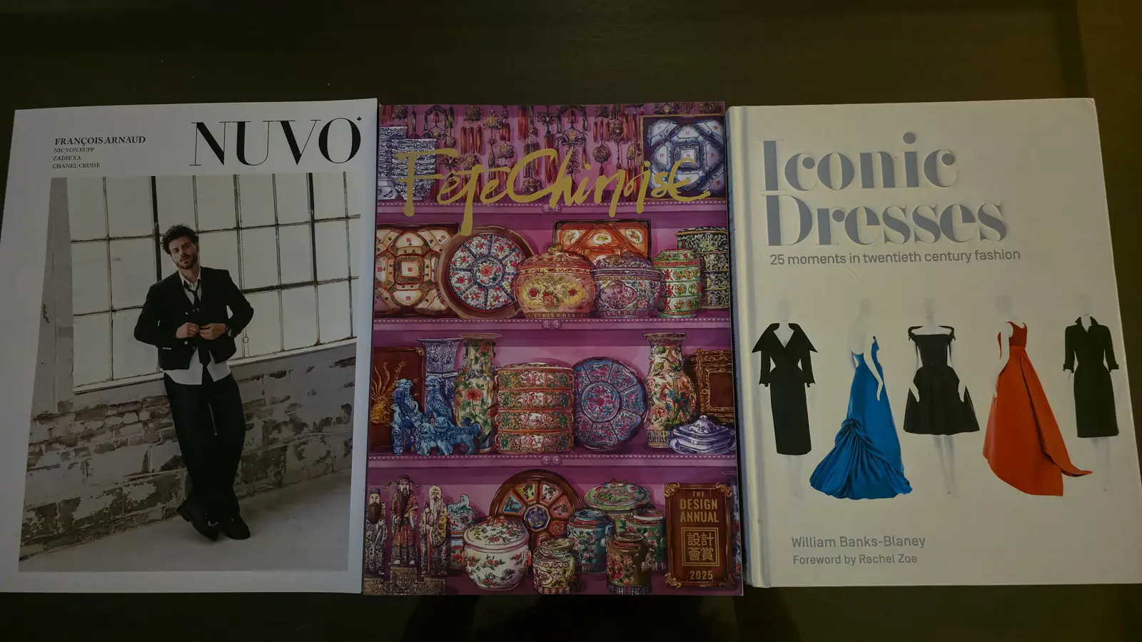 NUVO magazine, the FĂȘte Chinoise 2025 design annual and the book Iconic Dresses on a dark coffee table, Shangri-La Toronto