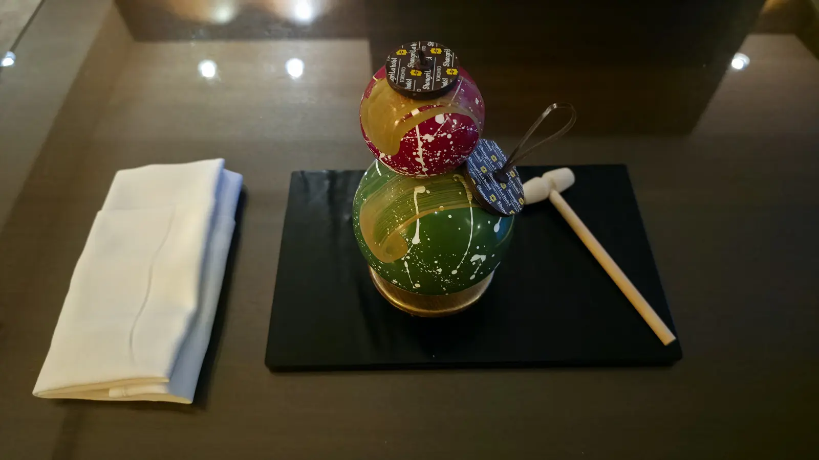 A Christmas chocolate ornament of two painted spheres with a mini wooden hammer, left in a Shangri-La Toronto suite