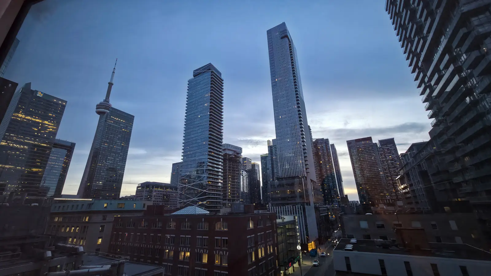 The view from a Shangri-La Toronto suite at dusk: the CN Tower, the RBC tower and downtown skyscrapers with lit windows