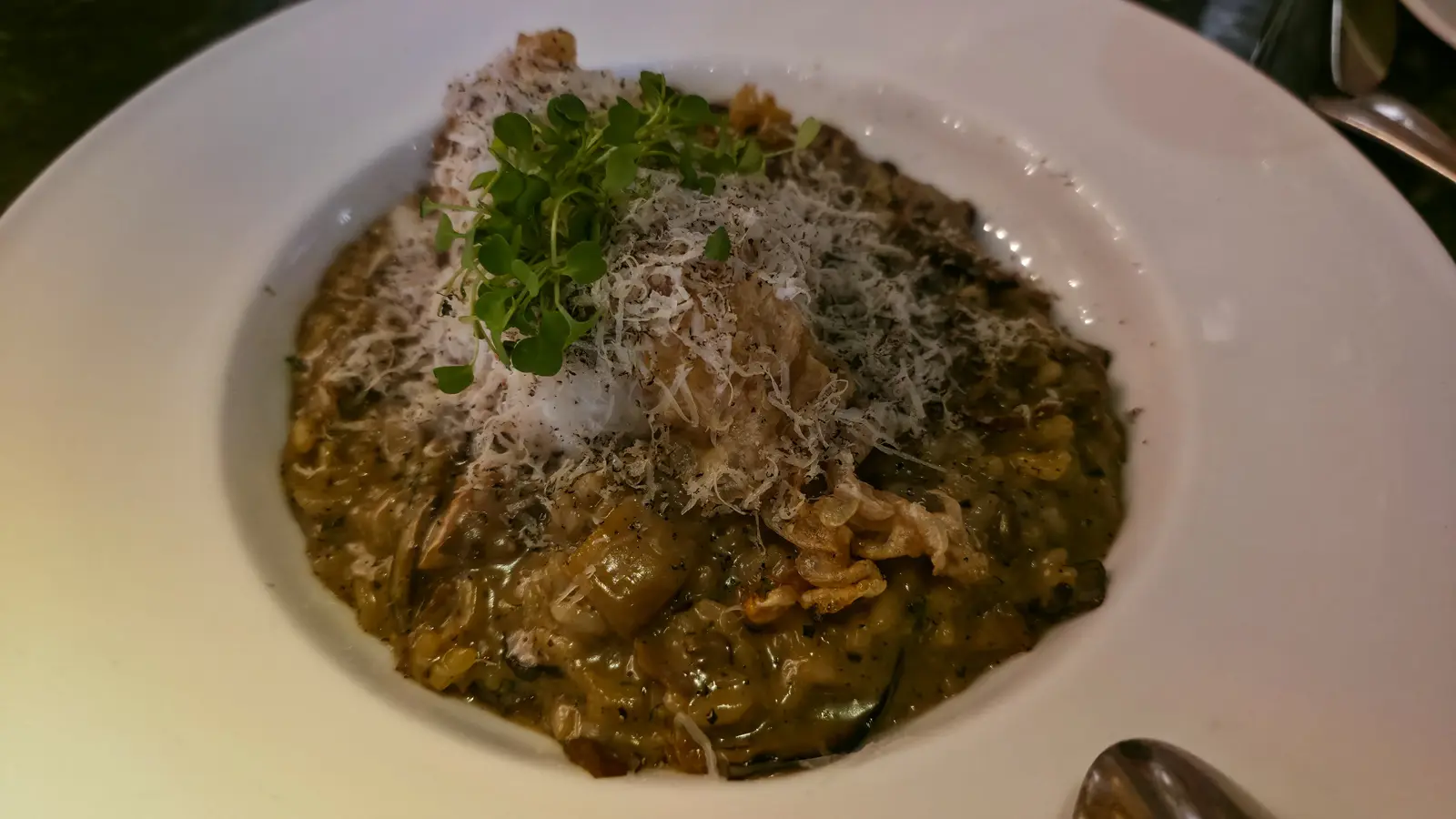 Mushroom risotto topped with grated cheese, cress and a crisp garnish in a wide white bowl at The Duchess, Amsterdam