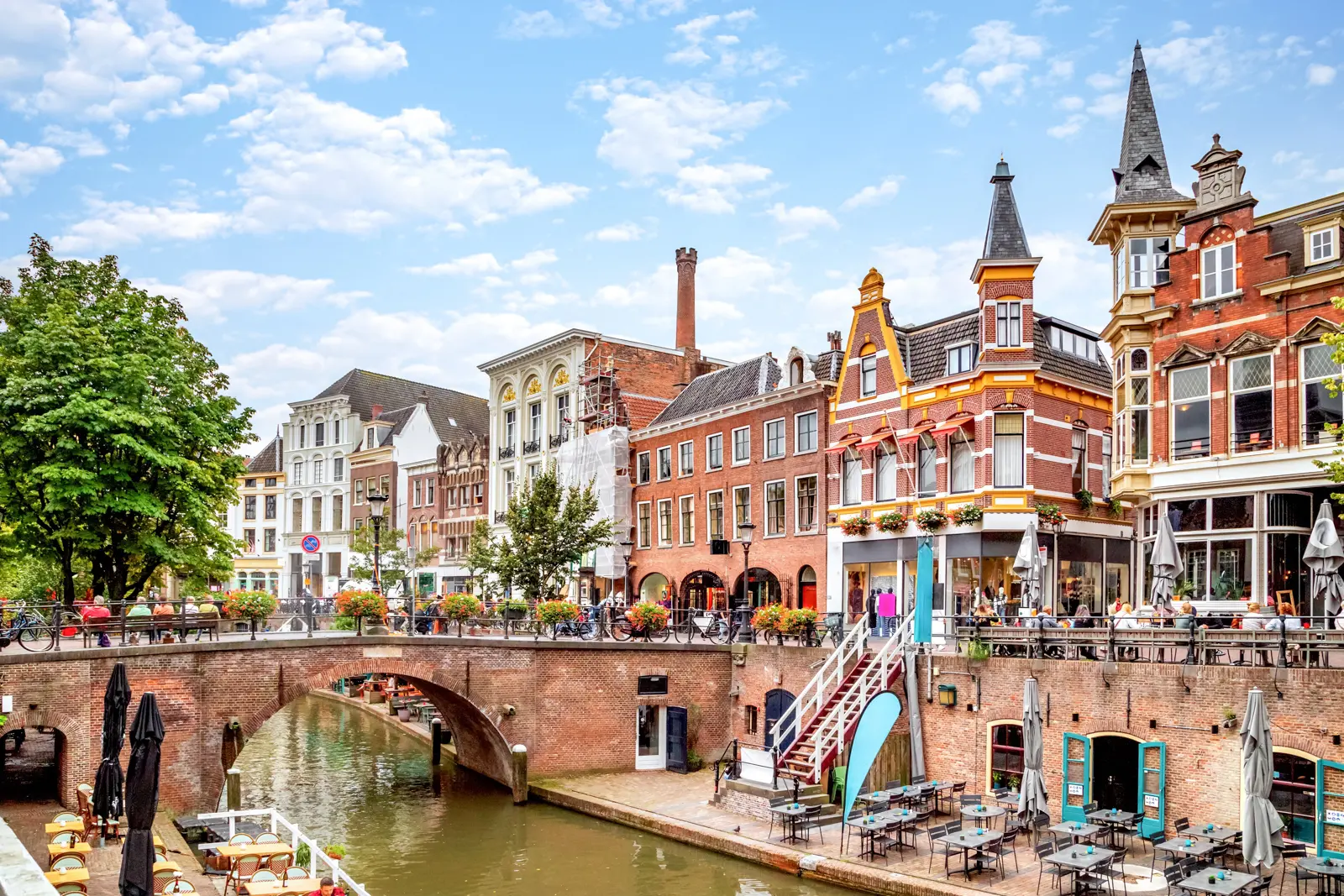 The Oudegracht in Utrecht, with a brick bridge, canal-side terraces and gabled houses above the water