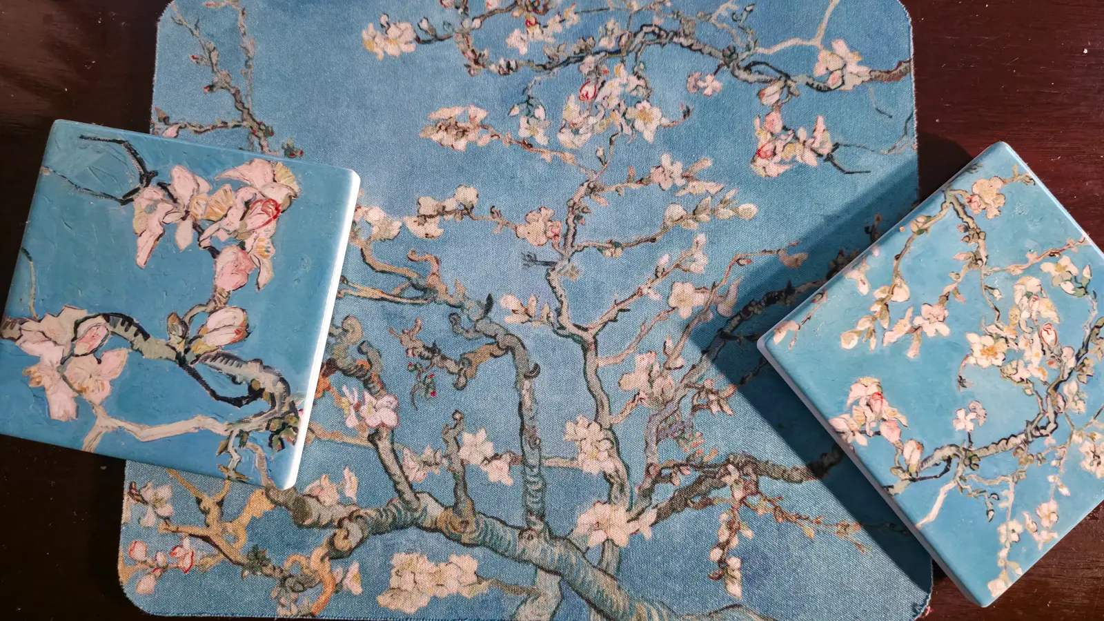 Almond Blossom coasters and a mouse pad, pale blossom on twisting branches against a turquoise sky, at home
