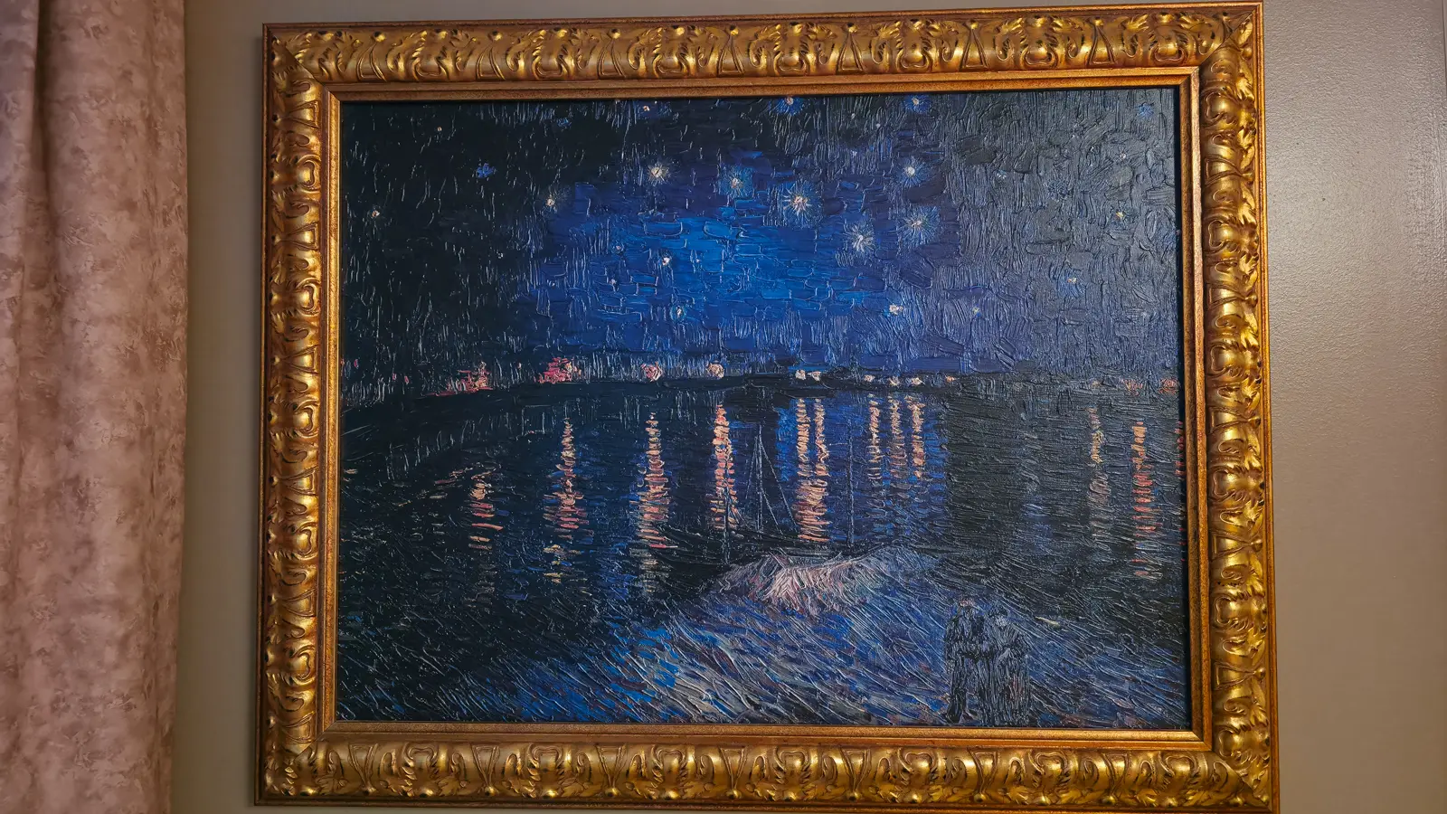 A framed Starry Night over the Rhone replica, deep navy and gold, in an ornate gilt frame at home