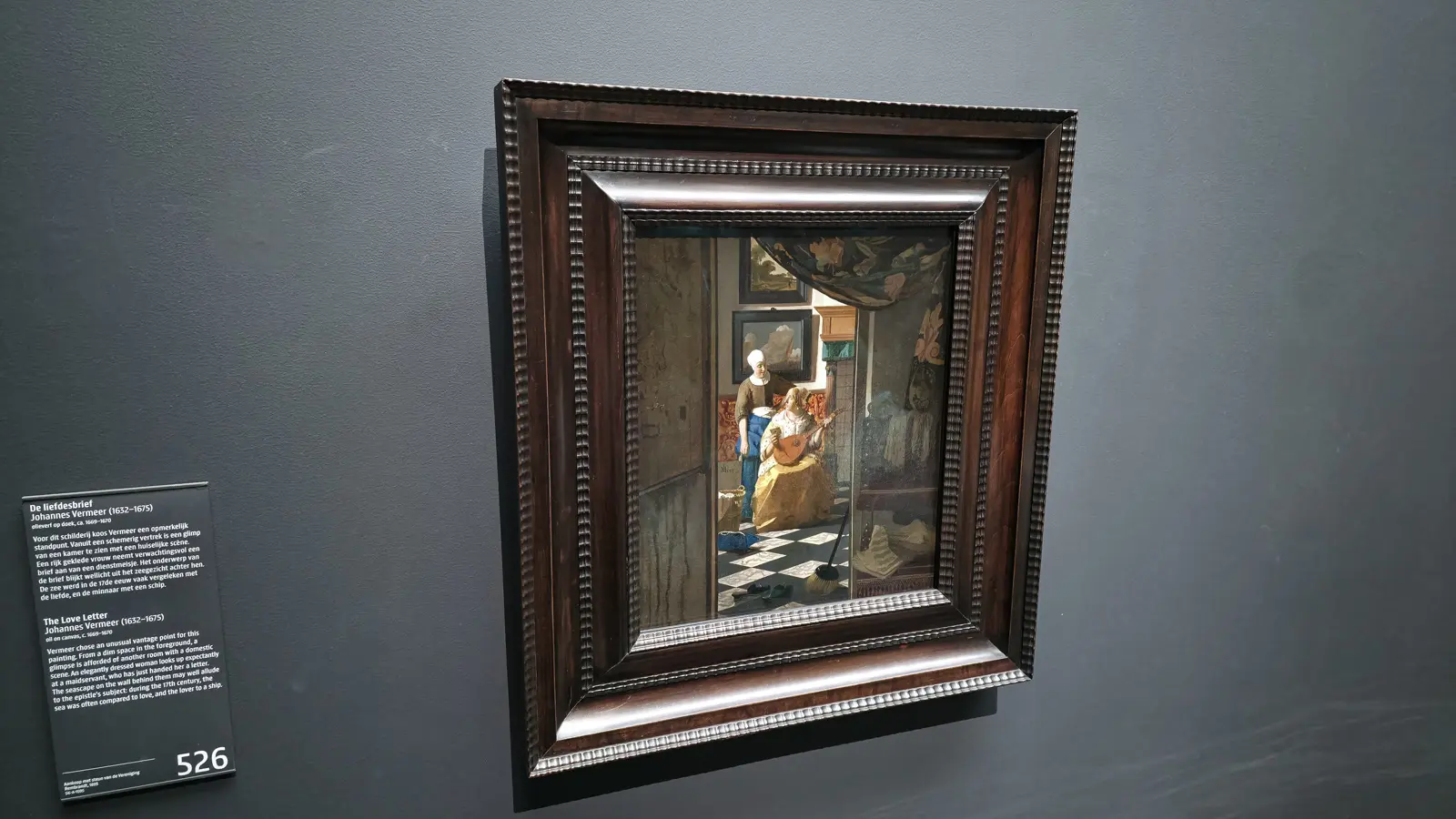 Vermeer's The Love Letter in a dark wooden frame at the Rijksmuseum, a maid handing a letter to a woman with a lute